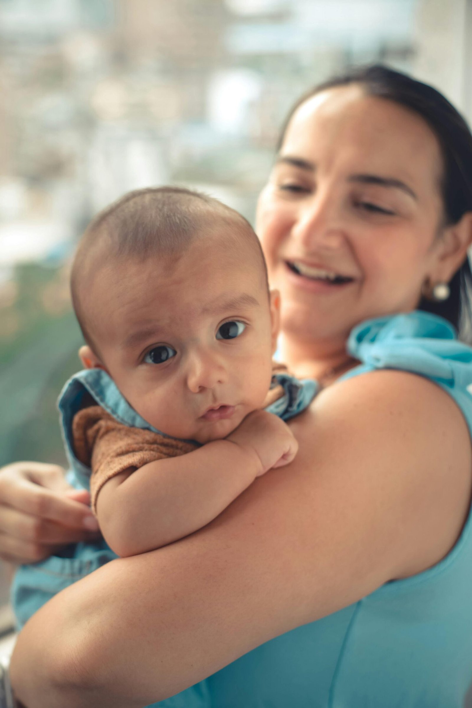 A joyful mother holding her baby indoors, showcasing a warm family moment with natural light.